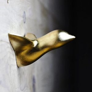 Ein goldener Vogel in der Dämmerung einer Wand, angebracht mit einem Nagel, konzipiert von Thomas Poganitsch in Wien