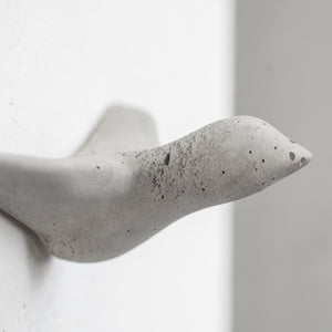 wandhaken in der form eines grauen vogels an einer weißen wand
